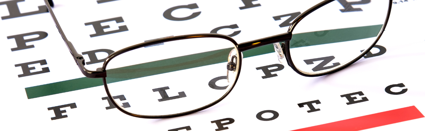 Kuvituskuvassa silmälääkärin näkötaulun, jossa kirjaimia, päällä on silmälasit.